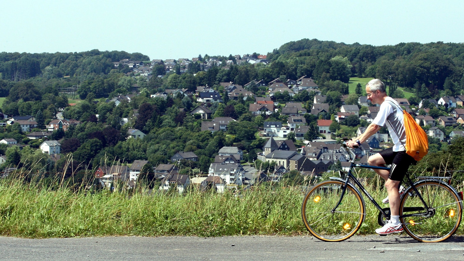 Das Foto zeigt einen Radfahrer auf einer Straße. Im Hintergrund die Silhouette von Kürten.