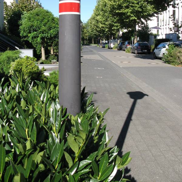 Am Mast einer Straßenlaterne ist eine rote Banderole angebracht, was bedeutet, dass diese Lampe nicht die ganze Nacht brennt.