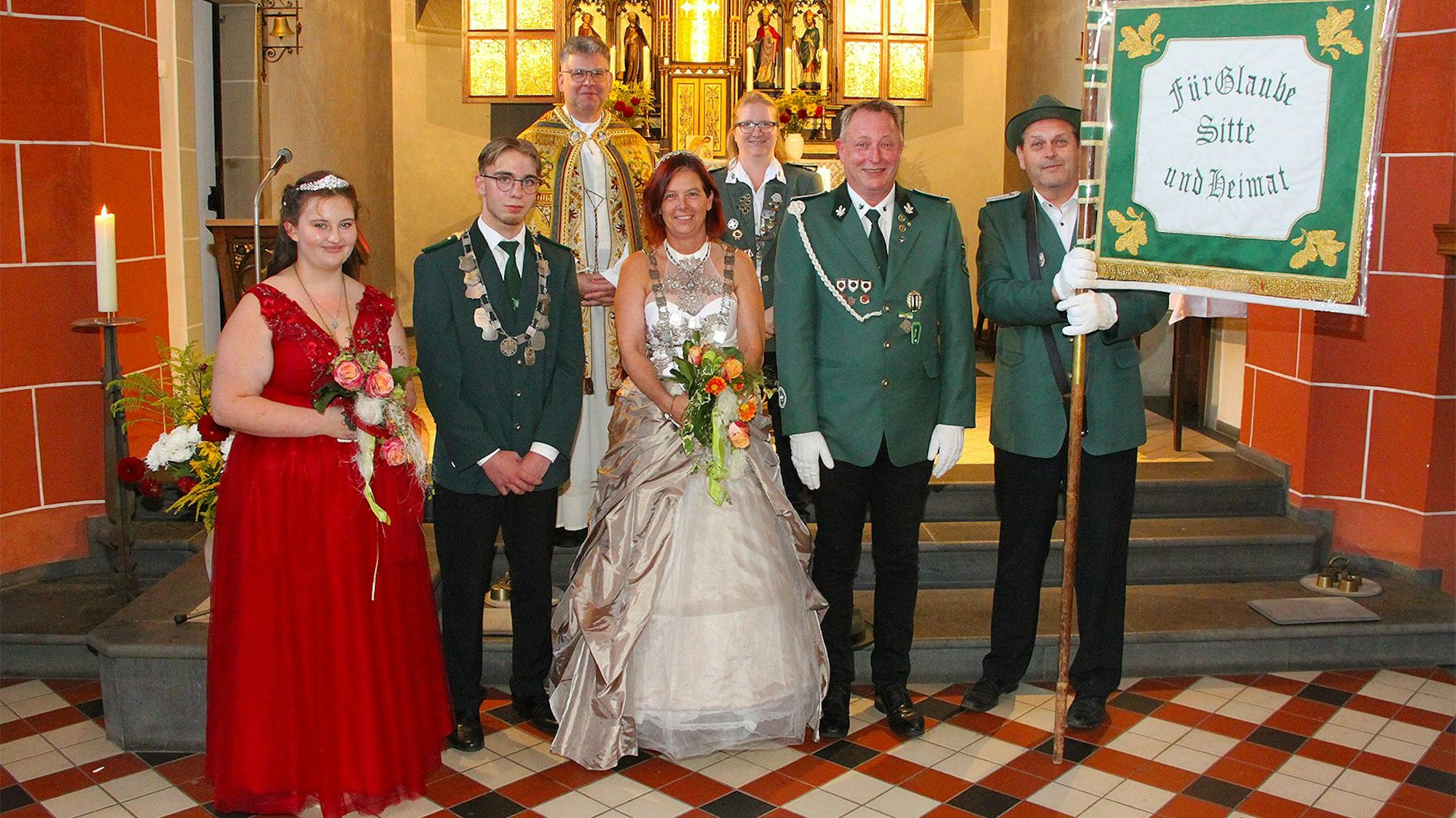 Schützen aus Rohr-Lindweiler und Königin Claudia Stern (M.) stehen in Uniform und festlicher Kleidung vor dem Altar in der Kirche.