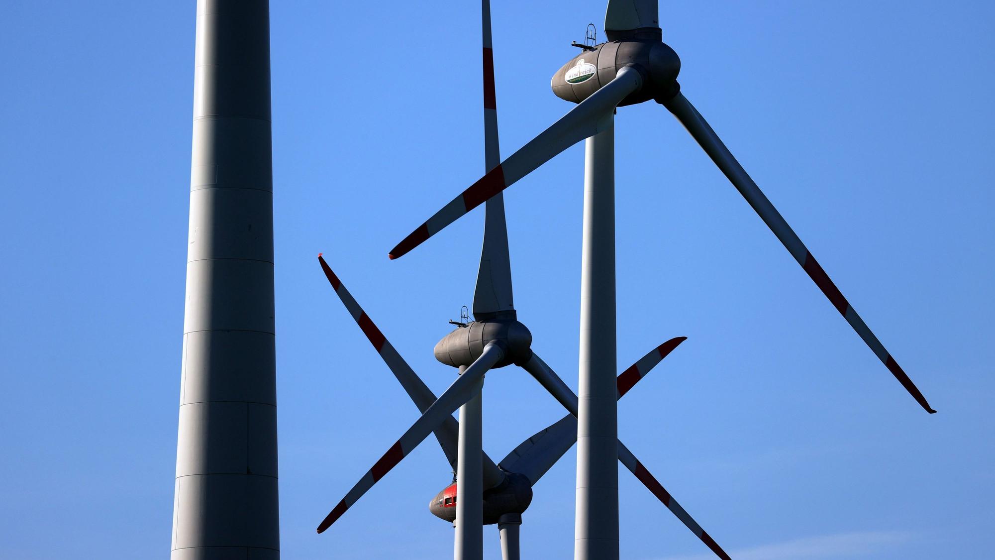 Windräder drehen sich vor blauem Himmel.