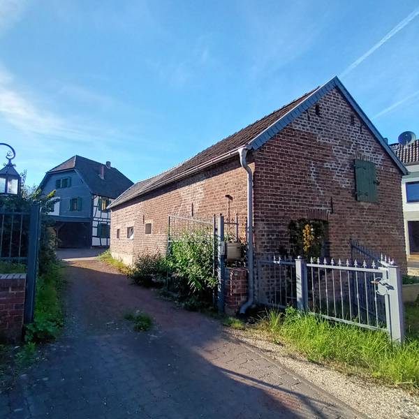 Eine Einfahrt führt zu einem Fachwerkwohnhaus