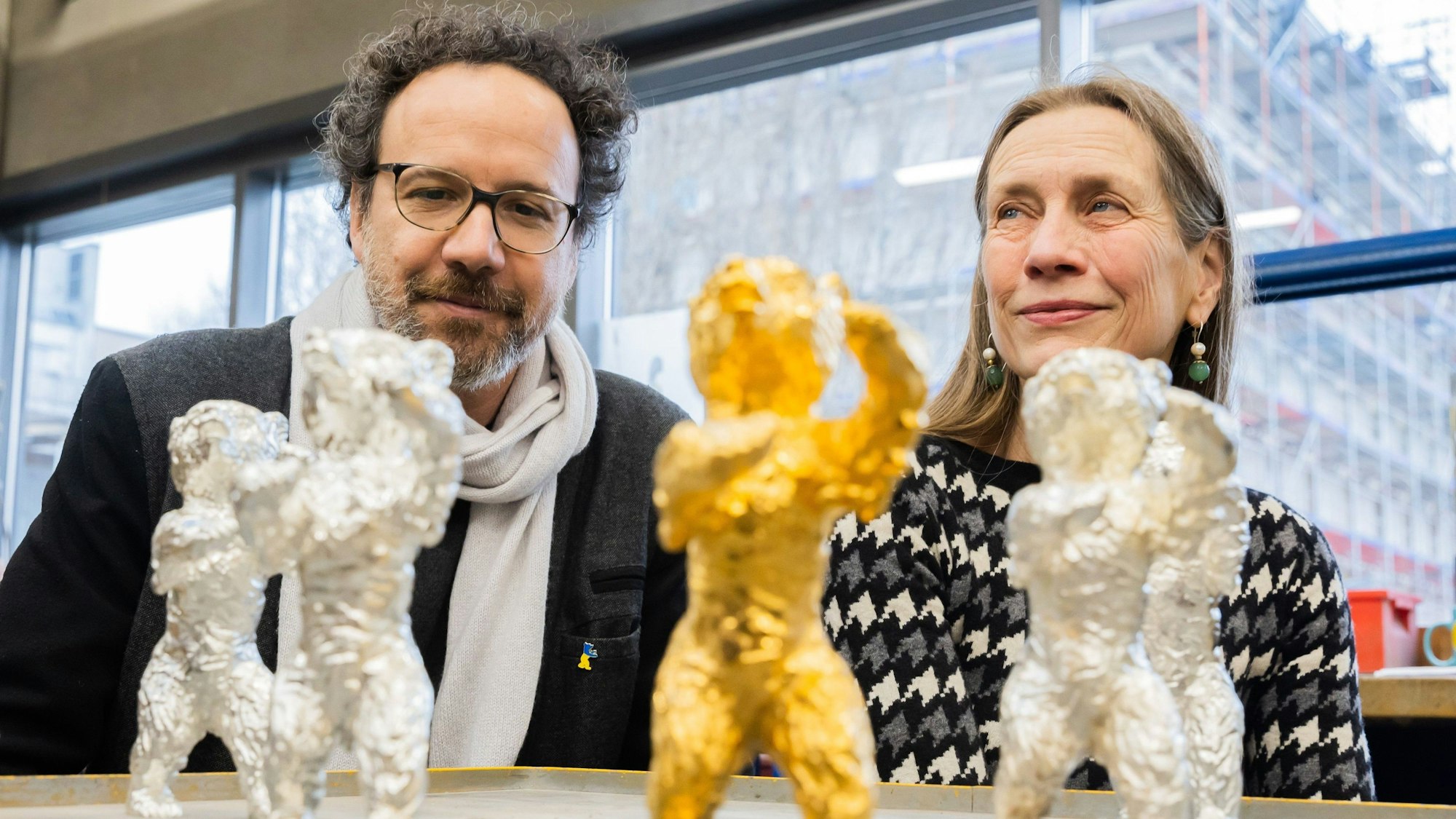 Das Leitungs-Duo der Berlinale, Carlo Chatrian, künstlerischer Direktor, und Mariette Rissenbeek, Geschäftsführerin, sitzen in der Bildgießerei Hermann Noack hinter Berlinale-Bären.