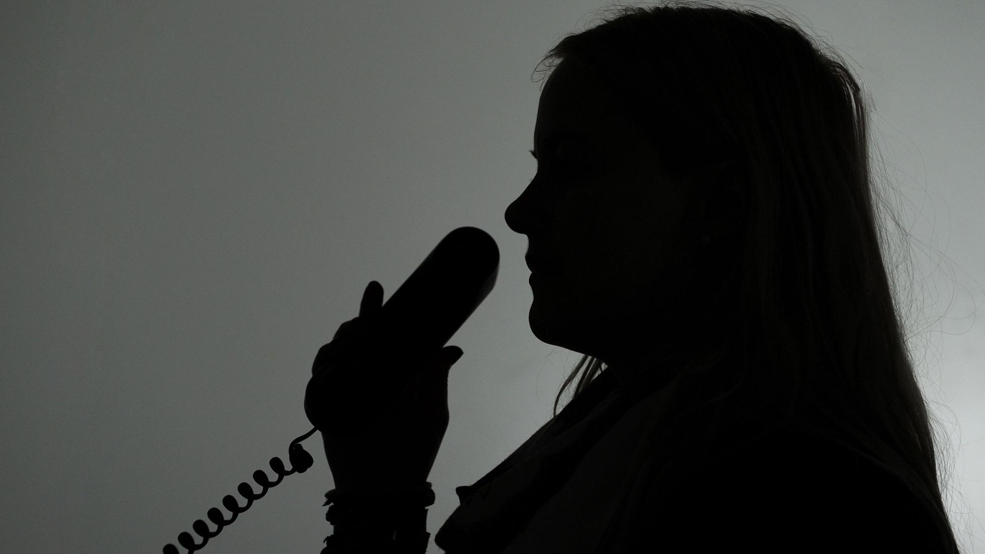 Eine Frau hält einen Telefonhörer (gestellte Aufnahme, Symbolbild).
