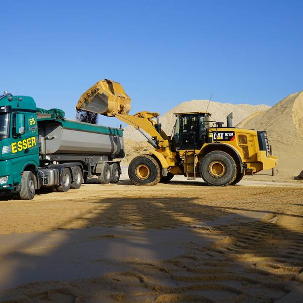 Ein Bagger lädt Sand auf einen Lkw.