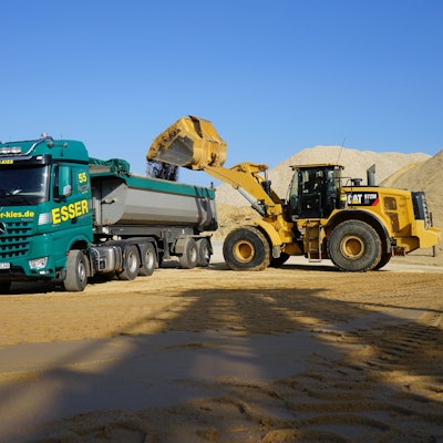 Ein Bagger lädt Sand auf einen Lkw.