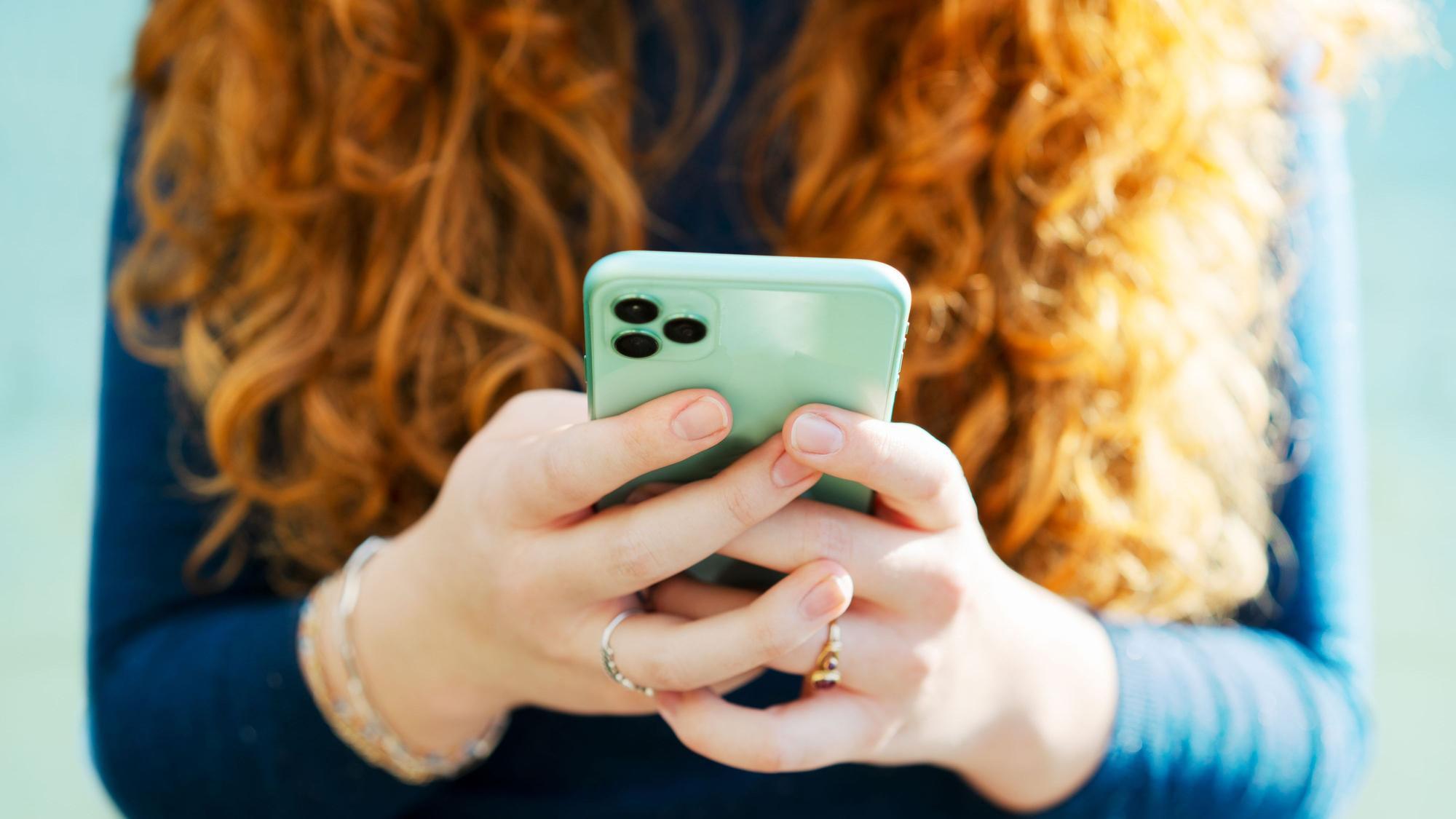 Junge Frau spielt mit ihrem Handy.
Getty Images / Tim Robberts