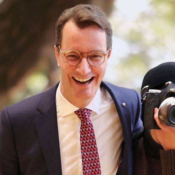 Auf einem gefälschten Bild ist Ministerpräsident Wüst zu sehen, wie er lachend einem Fotografen den Arm um die Schulter legt. Dessen Gesicht ist hinter einer Kamera verborge.