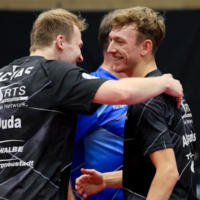 Tischtennis-Spieler Benedikt Duda umarmt seinen Mannschaftskollegen Adrien Rassenfosse.