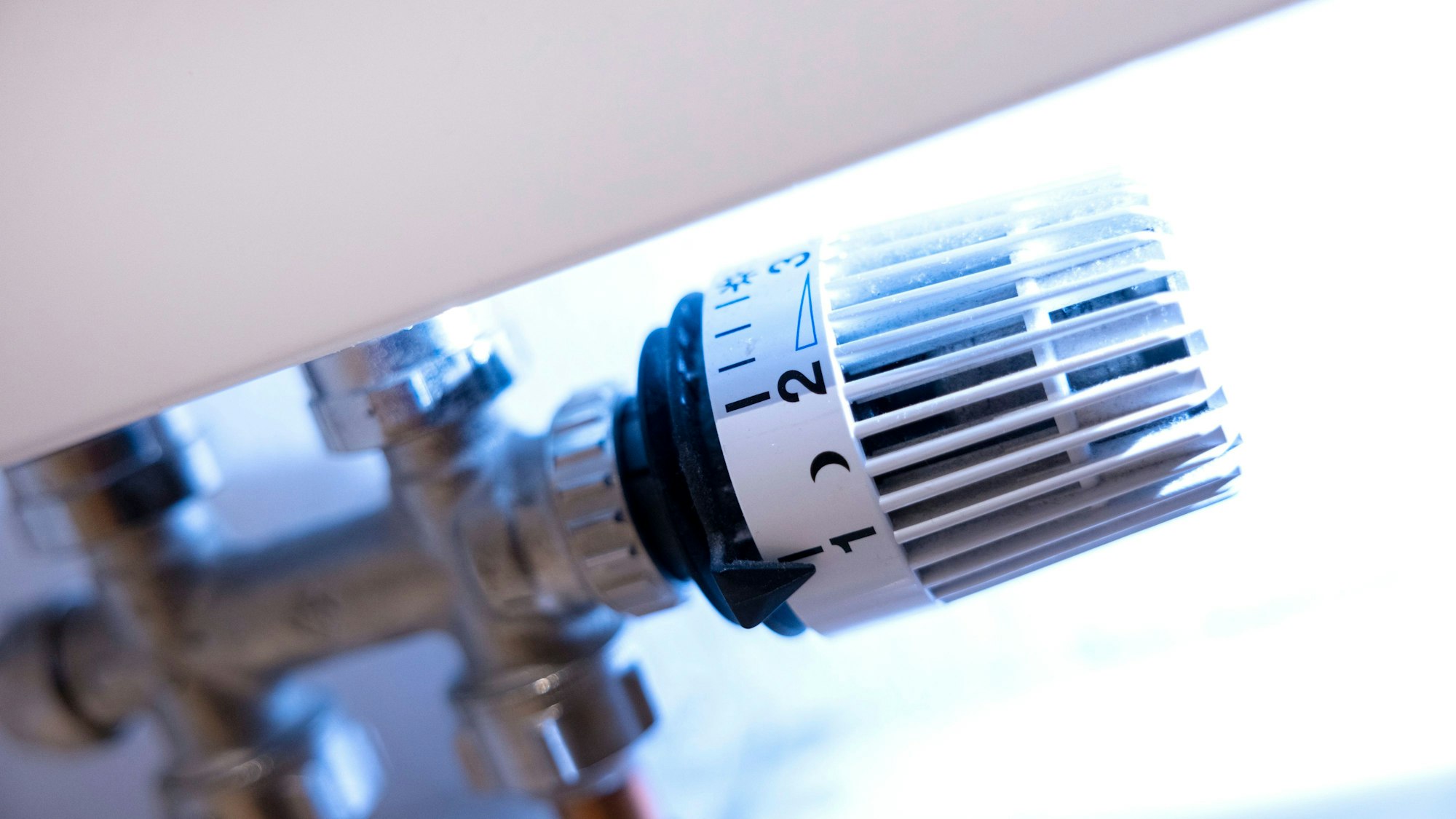 Ein Thermostat an der Heizung in einer Wohnung steht auf der Stufe 1, daneben sind ein Mond und die Stufe 2 zu sehen.