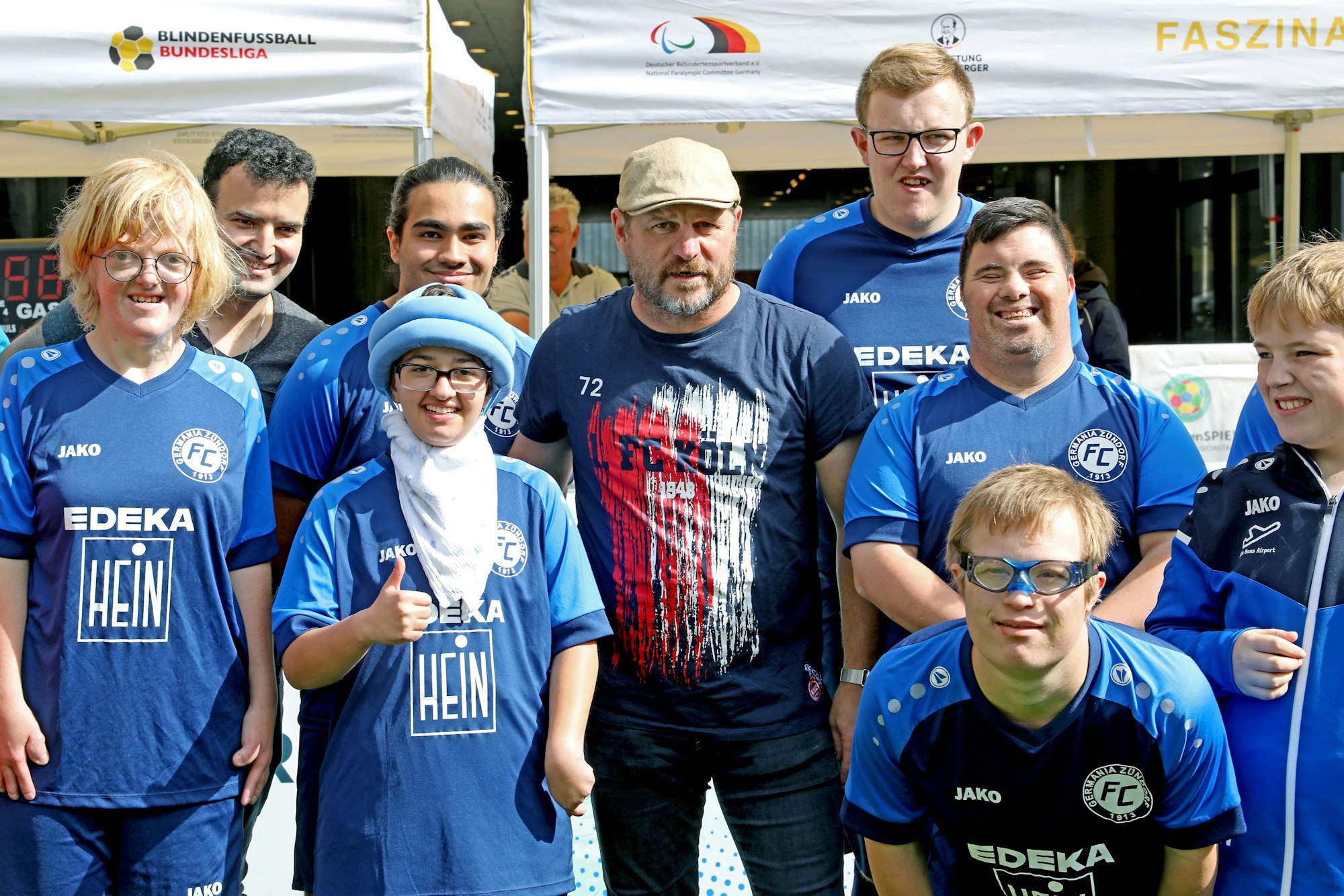 Steffen Baumgart steht inmitten einer Gruppe von Teilnehmern und Teilnehmerinnen der Fußball-Inklusionstage