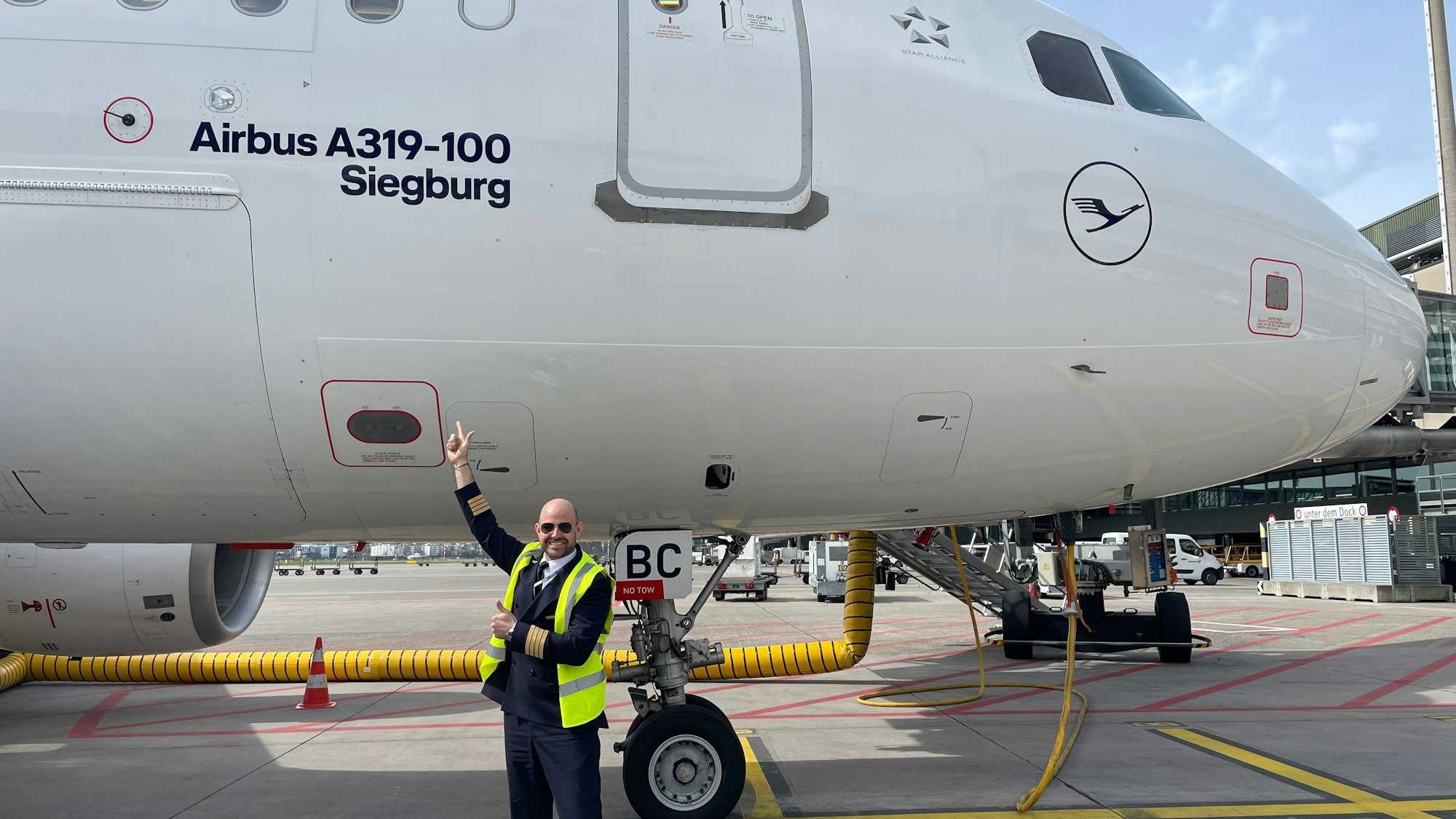 Ein Pilot steht auf dem Rollfeld vor einem Flugzeug.