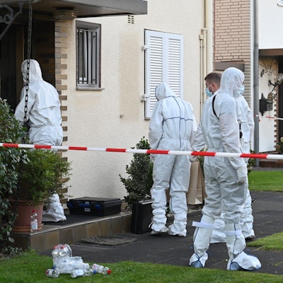 Das Bild zeigt Polizeibeamte in weißen Schutzanzügen am Tatort.
