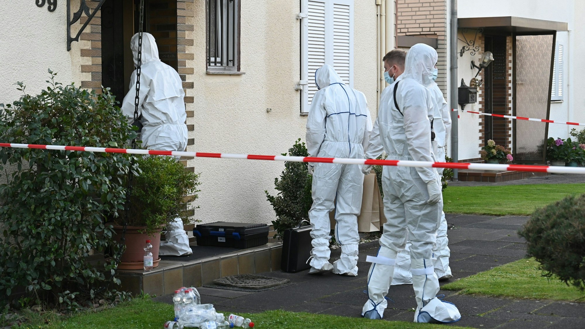 Das Bild zeigt Kripobeamte in weißen Schutzanzügen vor dem Haus des Rentners.