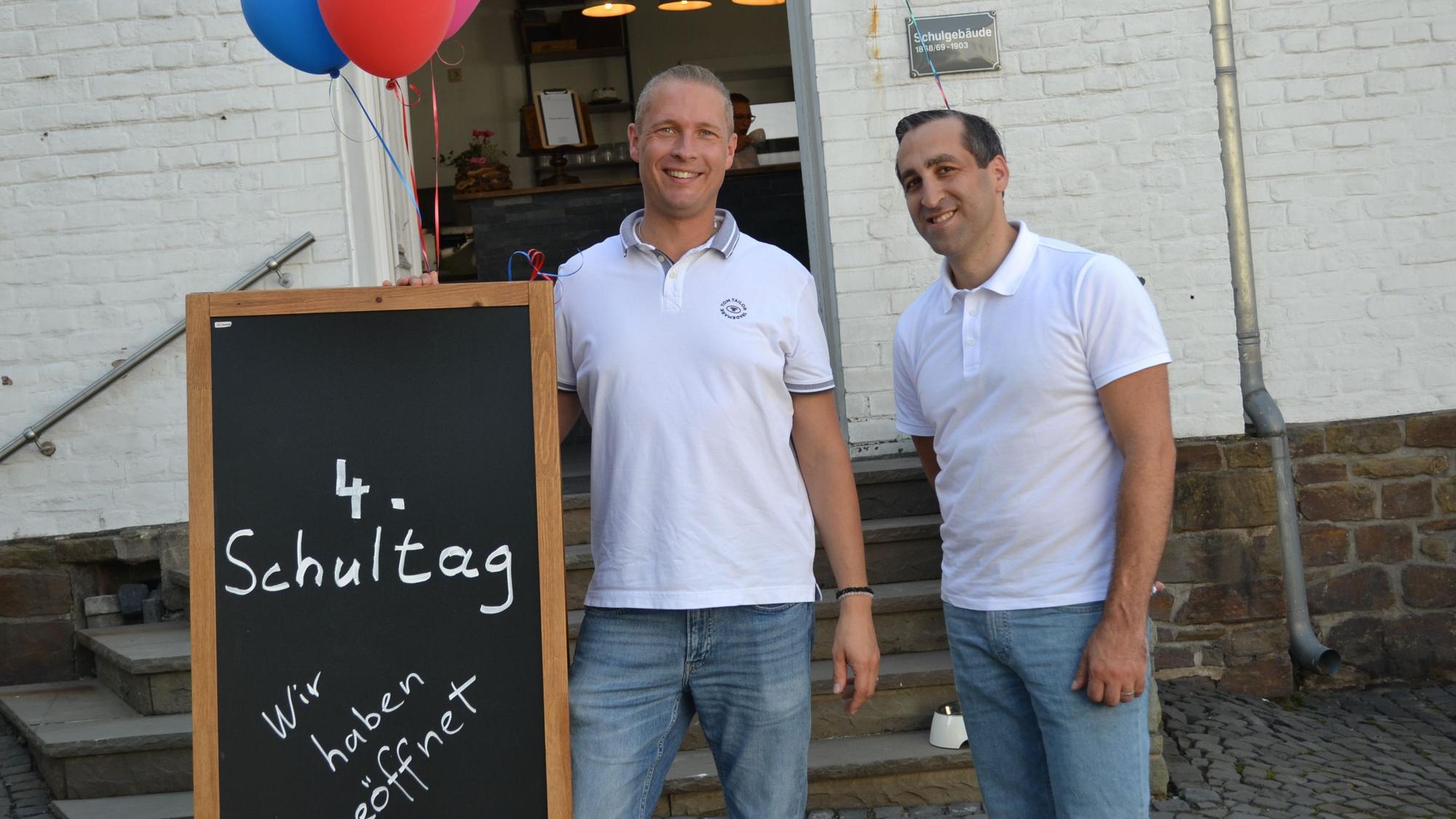 Zwei Männer stehen vor einem Café.