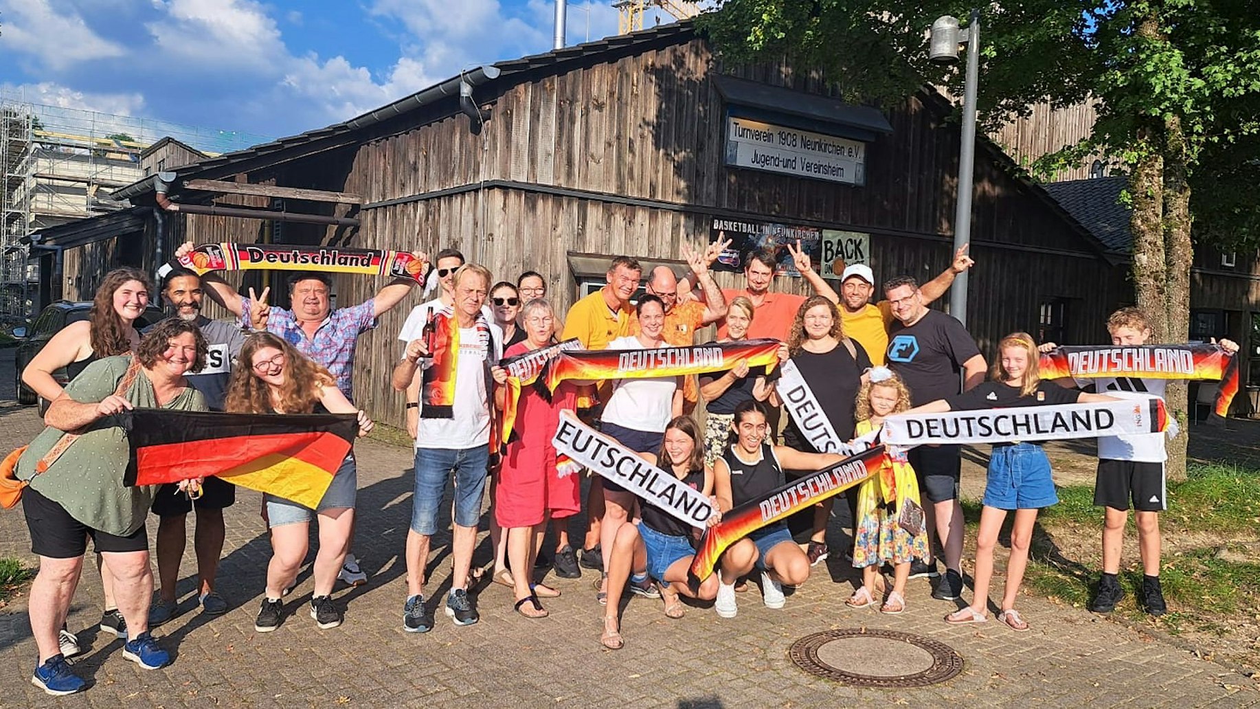 Eine Gruppe feiernder Fans steht vor einer Sporthalle.