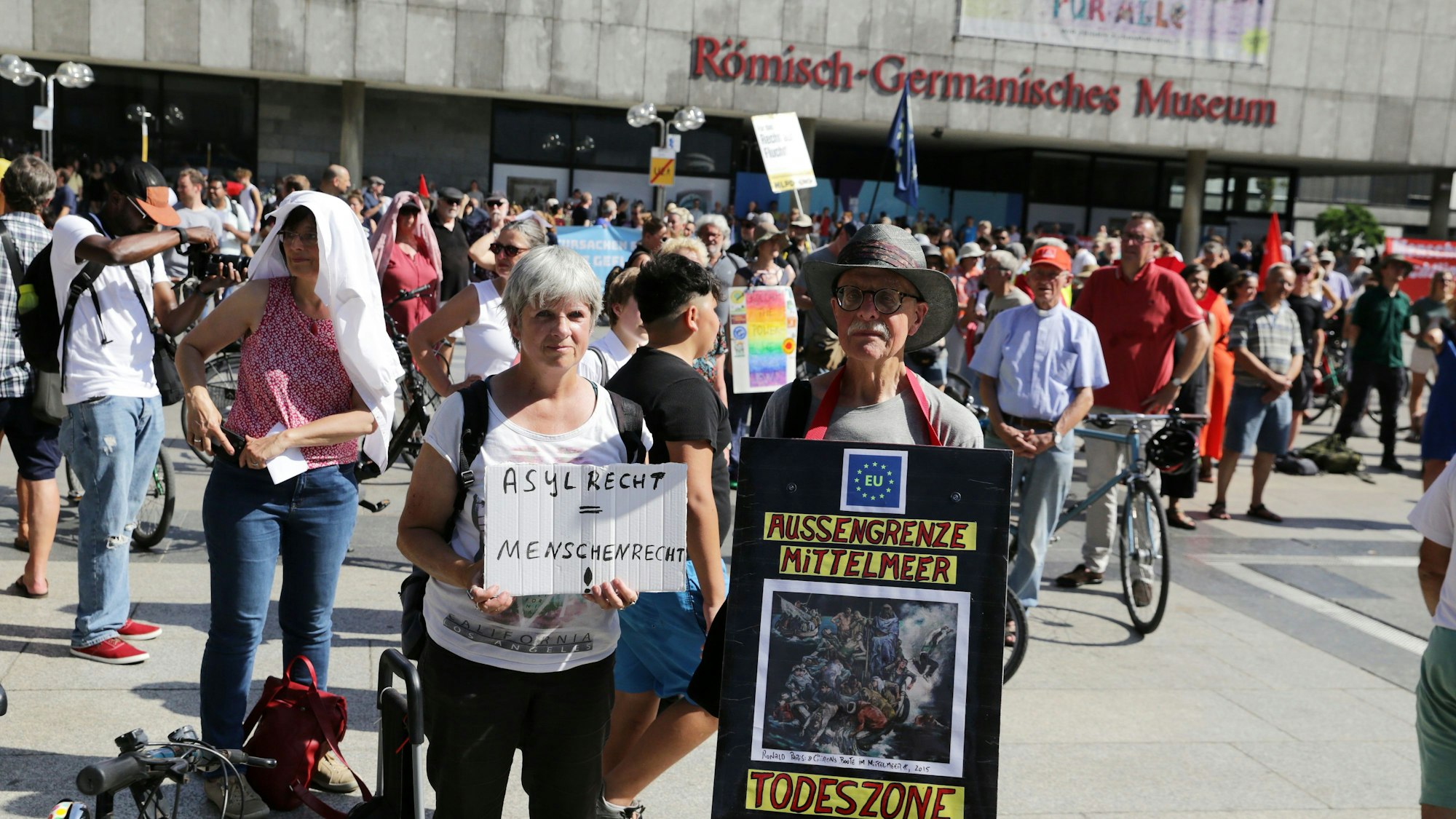 Demonstranten mit Plakaten auf dem Roncalliplatz: „Asylrecht ist Menschenrecht“
