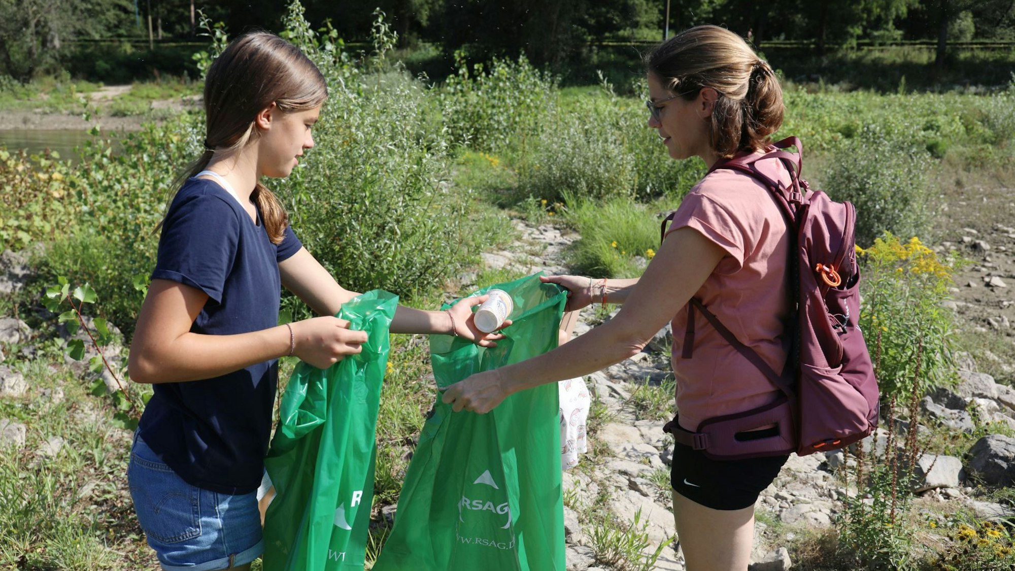 Zwei Mädchen sammeln Müll.