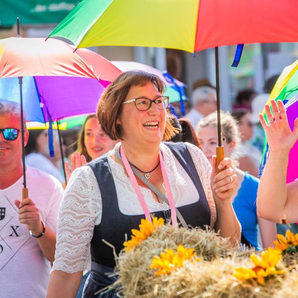 Teilnehmerinnen und Teilnehmer des Erntezugs mit bunten Regenschirmen