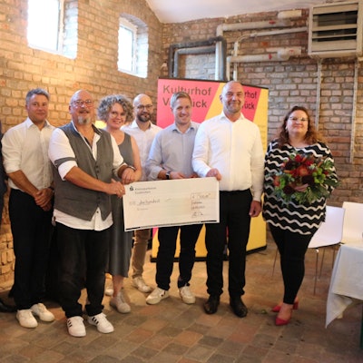 Eine Gruppe steht in einem Saal zusammen. Zwei Männer halten einen Scheck. Sie sind von der SPD im Kreis Euskirchen für ihr ehrenamtliches Engagement geehrt worden.