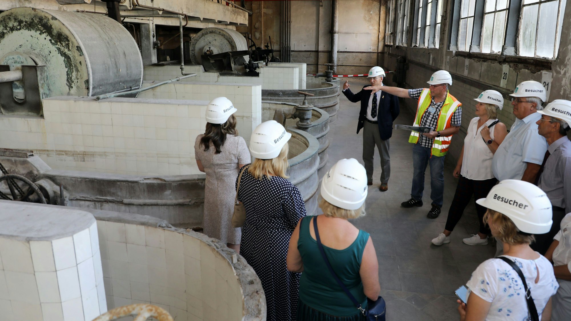 Frank Stugg erläutert einer Besuchergruppe historische Maschinen in einer Werkshalle der ehemaligen Papierfabrik Zanders.