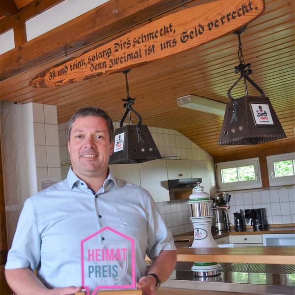 Stolz präsentiert Jan Wirths, Vorsitzender des Trägervereins „Alter Schulbezirk Wallerhausen“, den Heimat-Preis, den sein Verein 2021 für ein erstes Projekt am Dörfergemeinschaftshaus in Morsbach-Wallerhausen erhalten hat. Wirths steht in dem Saal, der künftig auch vermietet werden soll.