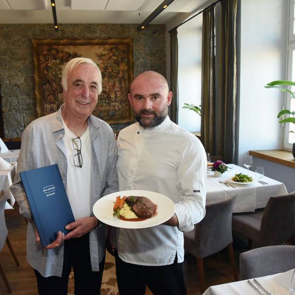 Klaus Ortlieb und Armend Mustafi stehen im Gastraum des „Hotels am Markt“ in Wipperfürth und zeigen ein Gericht von der neuen Speisekarte.