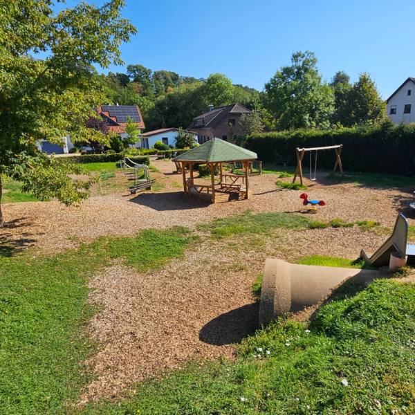 Zu sehen ist ein Spielplatz, auf dessen Fläche Holzhackschnitzel verteilt wurden.