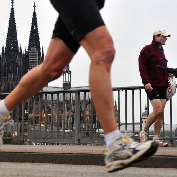 Ein Teilnehmer des Halbmarathons im Rahmen des Köln Marathons passiert in Köln vor der Kulisse des Doms die Deutzer Brücke.