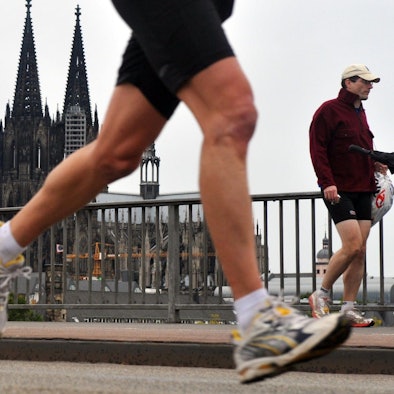 Ein Teilnehmer des Halbmarathons im Rahmen des Köln Marathons passiert in Köln vor der Kulisse des Doms die Deutzer Brücke.