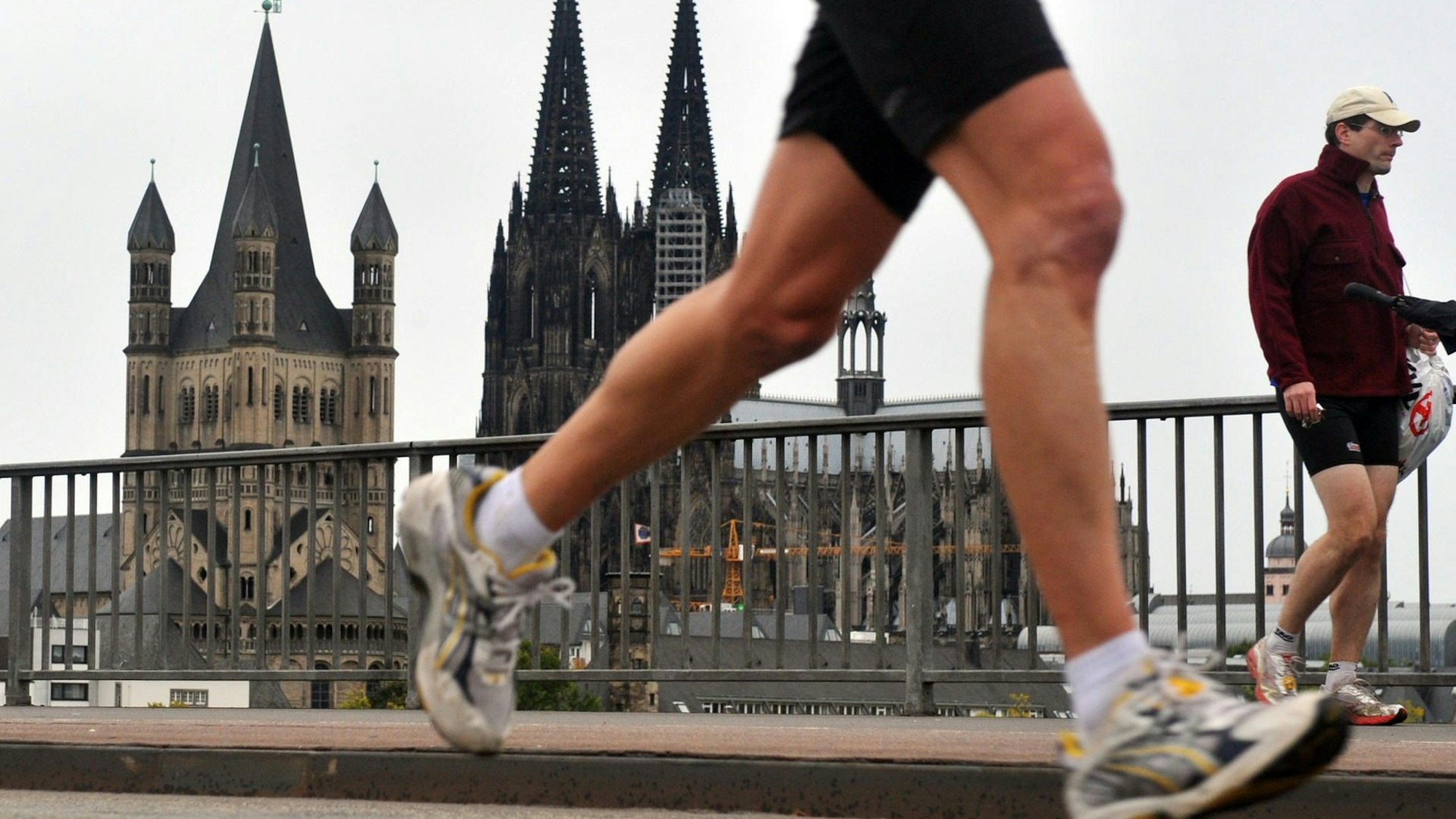 Ein Teilnehmer des Halbmarathons im Rahmen des Köln Marathons passiert in Köln vor der Kulisse des Doms die Deutzer Brücke.