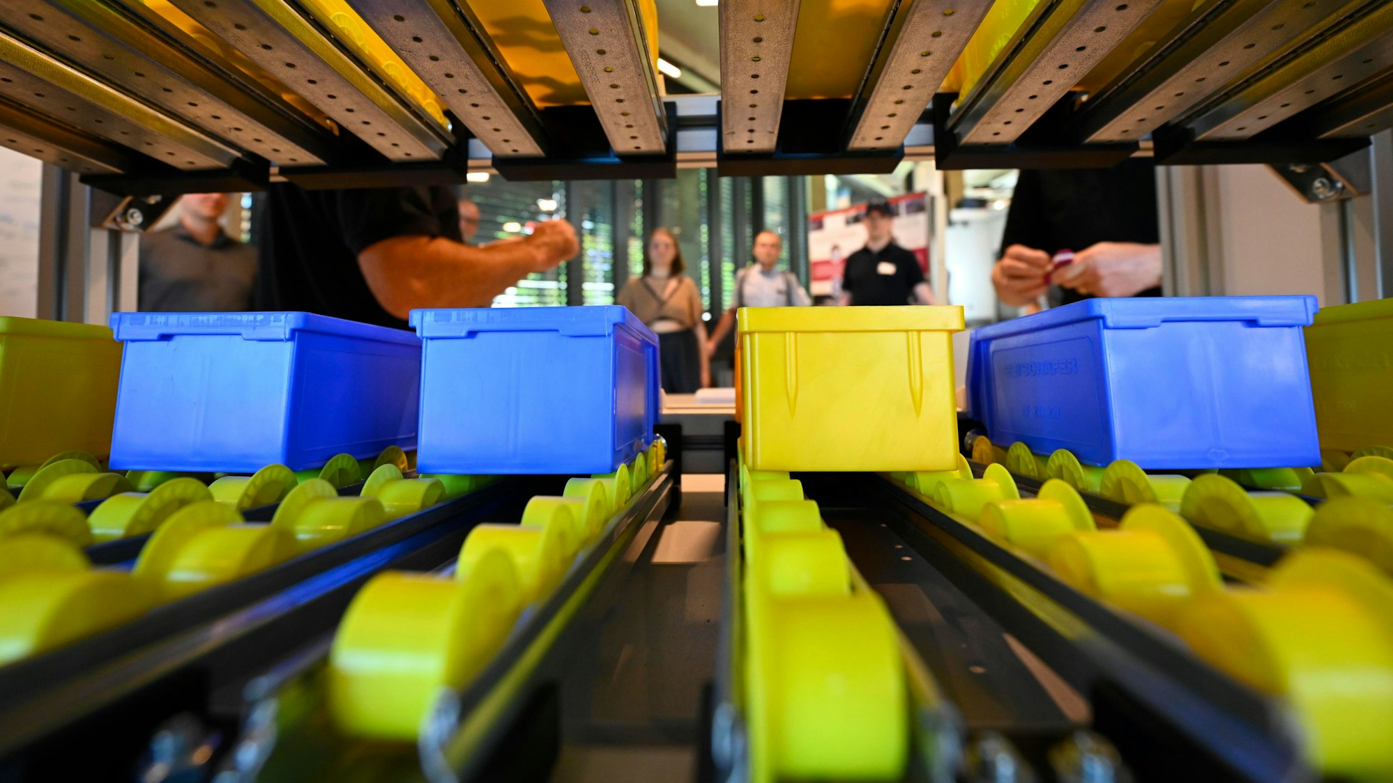 Blaue Plastikkisten stehen auf Schienen mit gelben Plastikrollen.