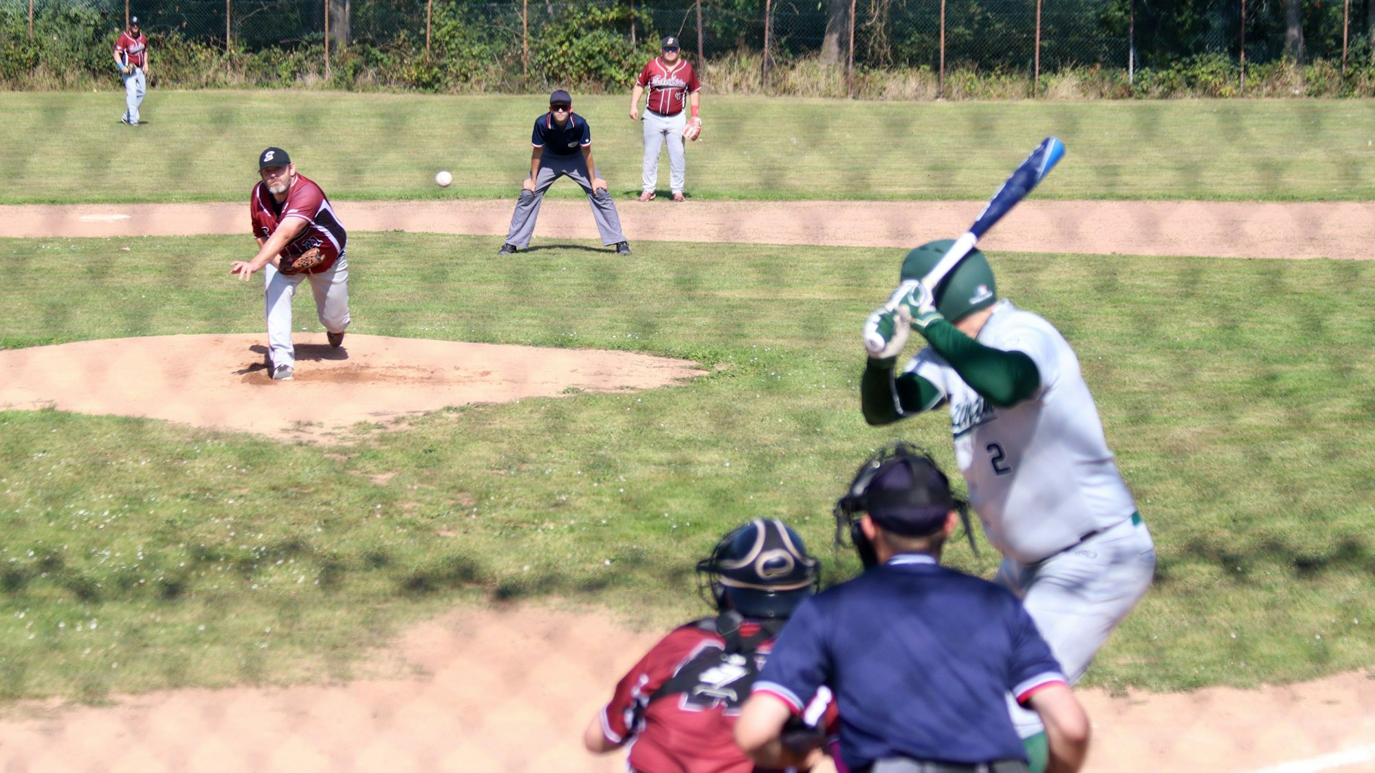 Ein Pitcher beim Baseball wirft einen Ball, der vom gegnerischen Batter erwartet wird.