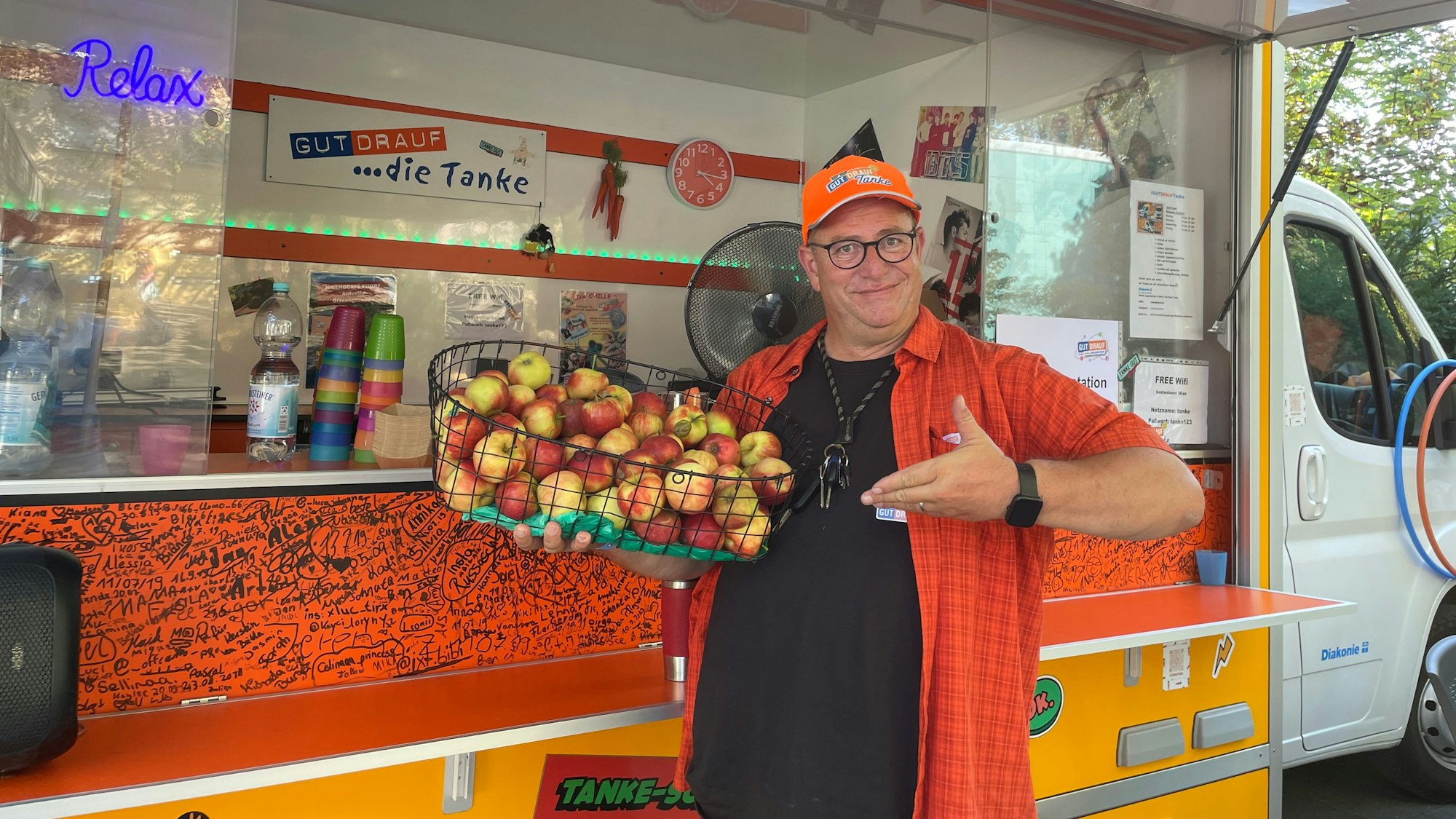 Jürgen Meyer steht mit einem Apfelkorb an dem Verkaufswagen, der Gut drauf-Tanke