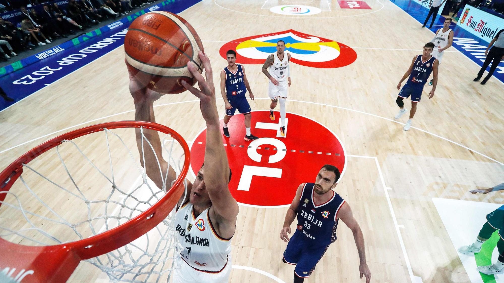 Germany's Johannes Voigtmann (L) dunks the ball against Serbia's Nikola Milutinov (R) during the FIBA Basketball World Cup final game against Serbia in Manila on September 10, 2023. (Photo by Yong Teck Lim / POOL / AFP)