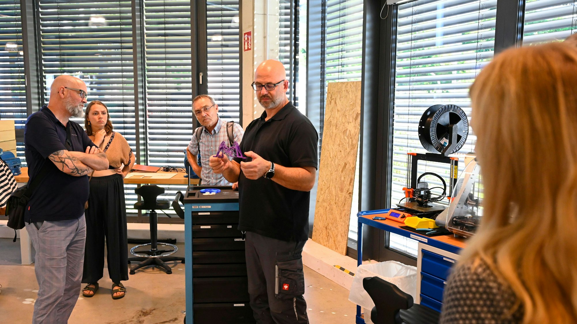 Ein Mann hält ein Modell in den Händen und erklärt dieses mehreren Zuhörerinnen und Zuhörern.