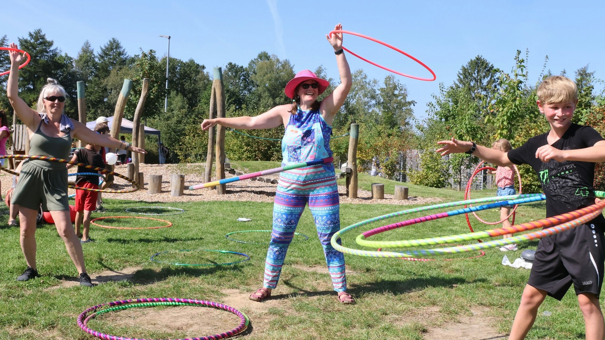 Zwei Frauen und ein Junge lassen Hula-Hoop-Reifen über ihren Hüften kreisen.
