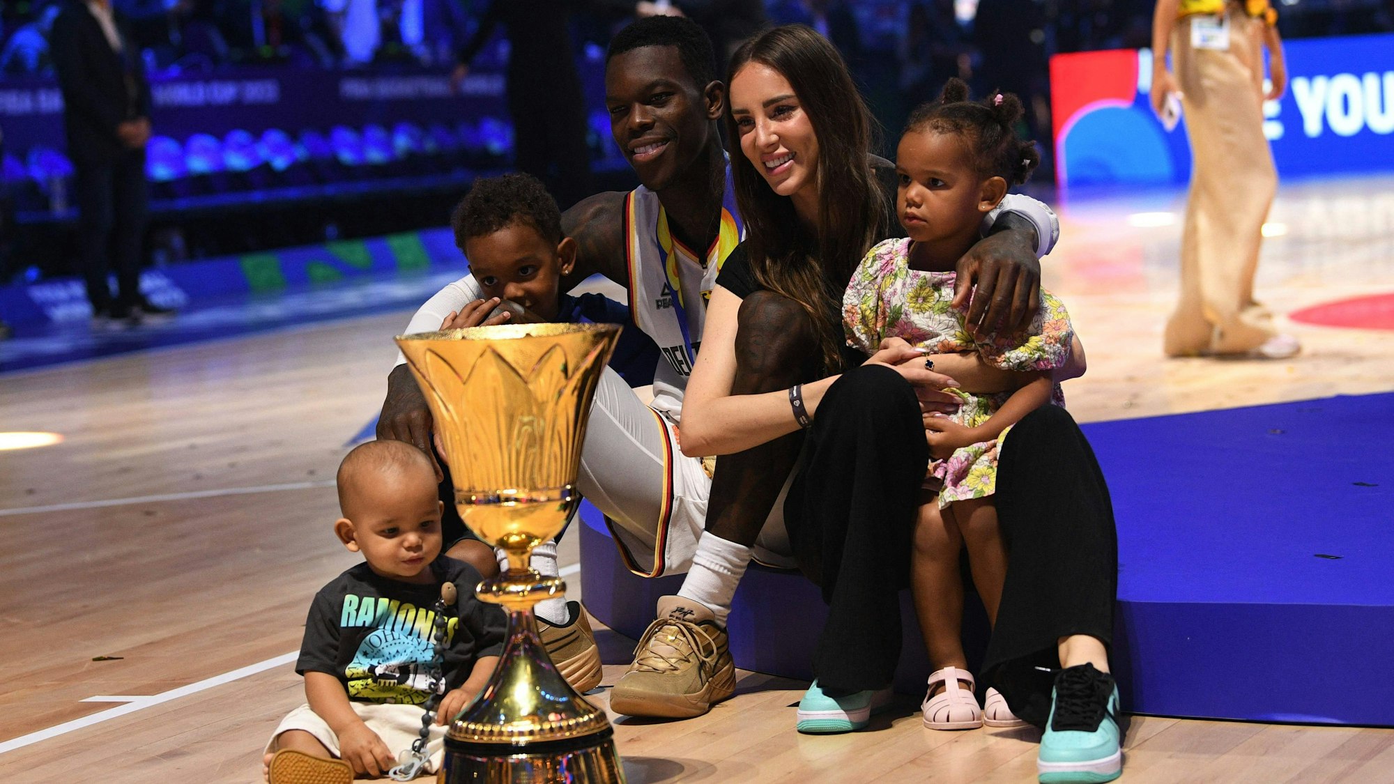 Dennis Schröder posiert mit seiner Familie und dem WM-Pokal.