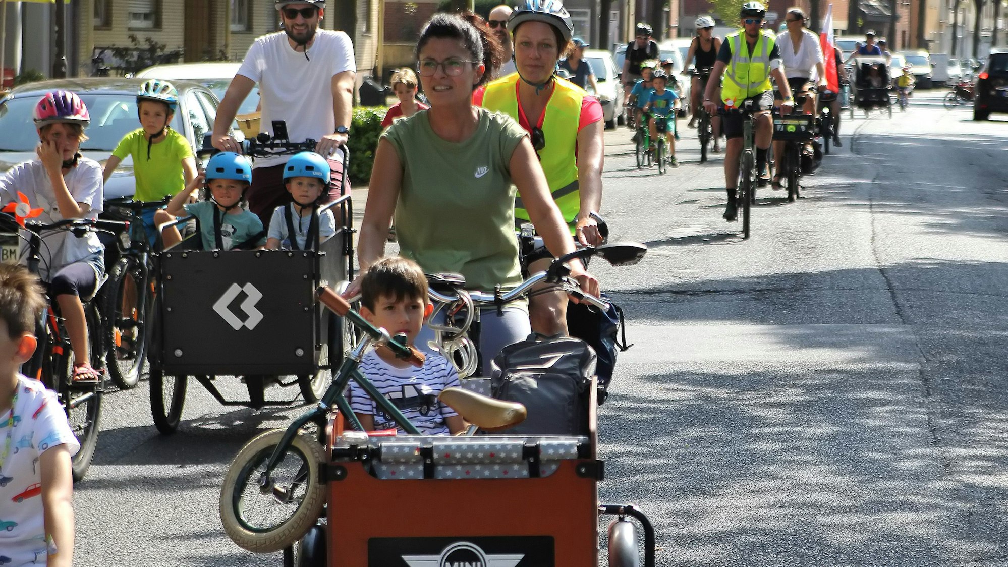 Zu sehen sind einige Radfahrer, die mit ihren Lastenrädern und Drahteseln eine Straße entlang fahren.
