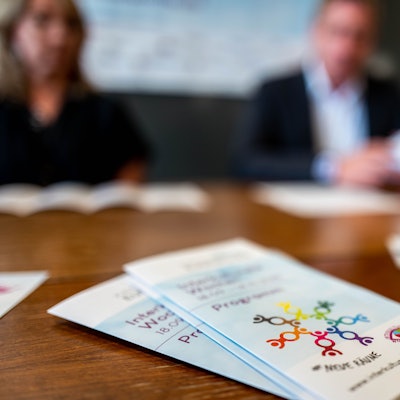 Das Bild zeigt den Flyer der Interkulturellen Wochen im Kreis Euskirchen. Im Hintergrund sind drei Menschen zu erahnen.