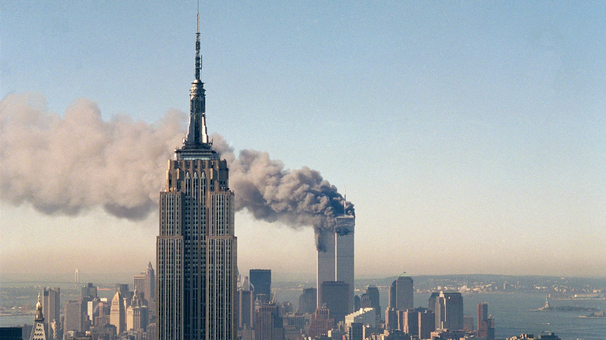 ARCHIV - 11.09.2001, USA, New York: Die Zwillingstürme des World Trade Centers brennen hinter dem Empire State Building. Fast 3000 Menschen kamen durch die verheerenden Attacken vor 22 Jahren ums Leben. Foto: Marty Lederhandler/AP/dpa +++ dpa-Bildfunk +++