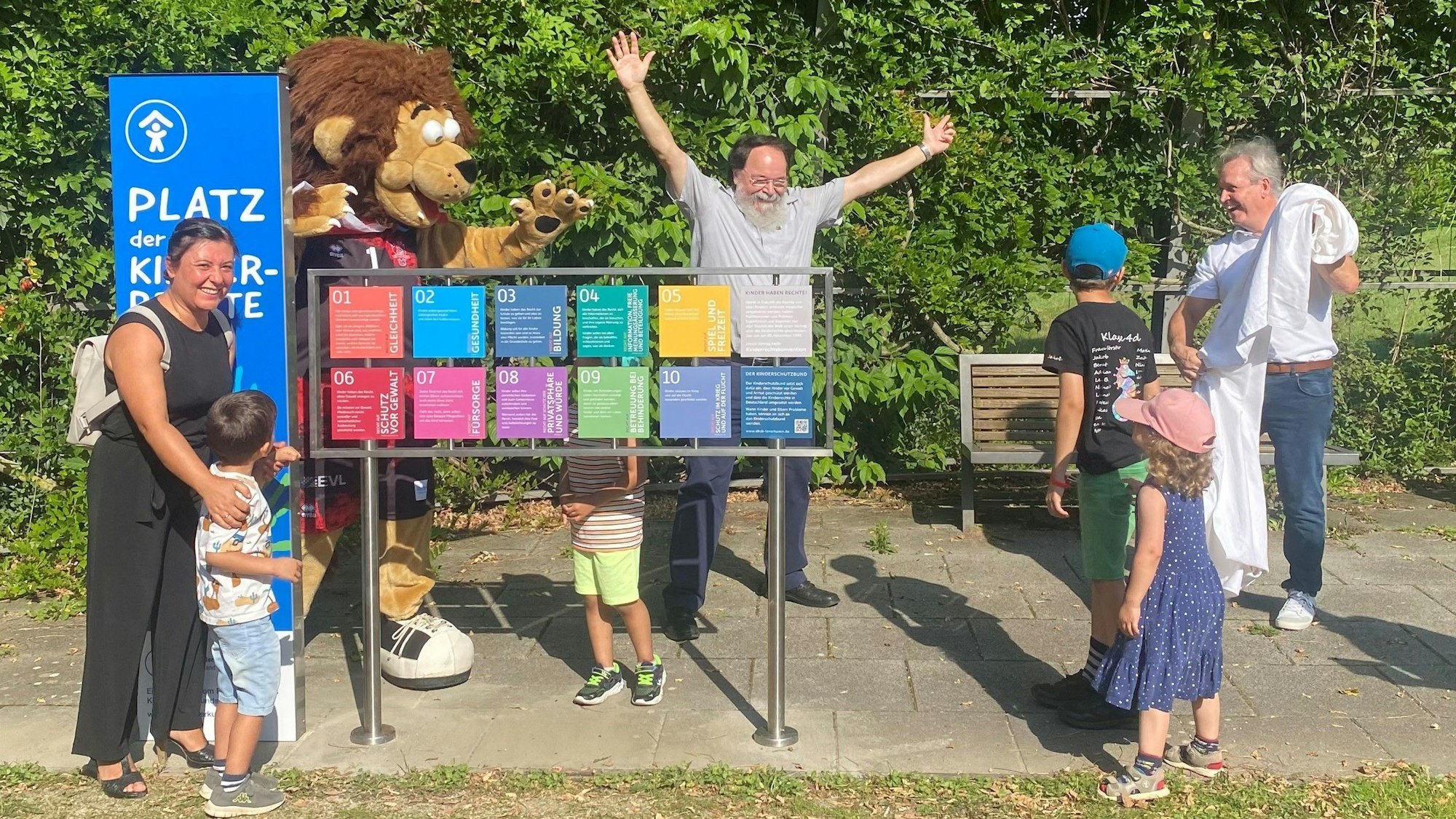 Gemeinsam mit Kindern weihen Lionel, Maskottchen der Bayer Giants, Helmut Ring, Kinderschutzbund, Bürgermeister Bernhard Marewski und und Sascha Wisniewski (r.), Vorsitzender des Fördervereins des Kinderschutzbundes, den Platz der Kinderrechte ein.