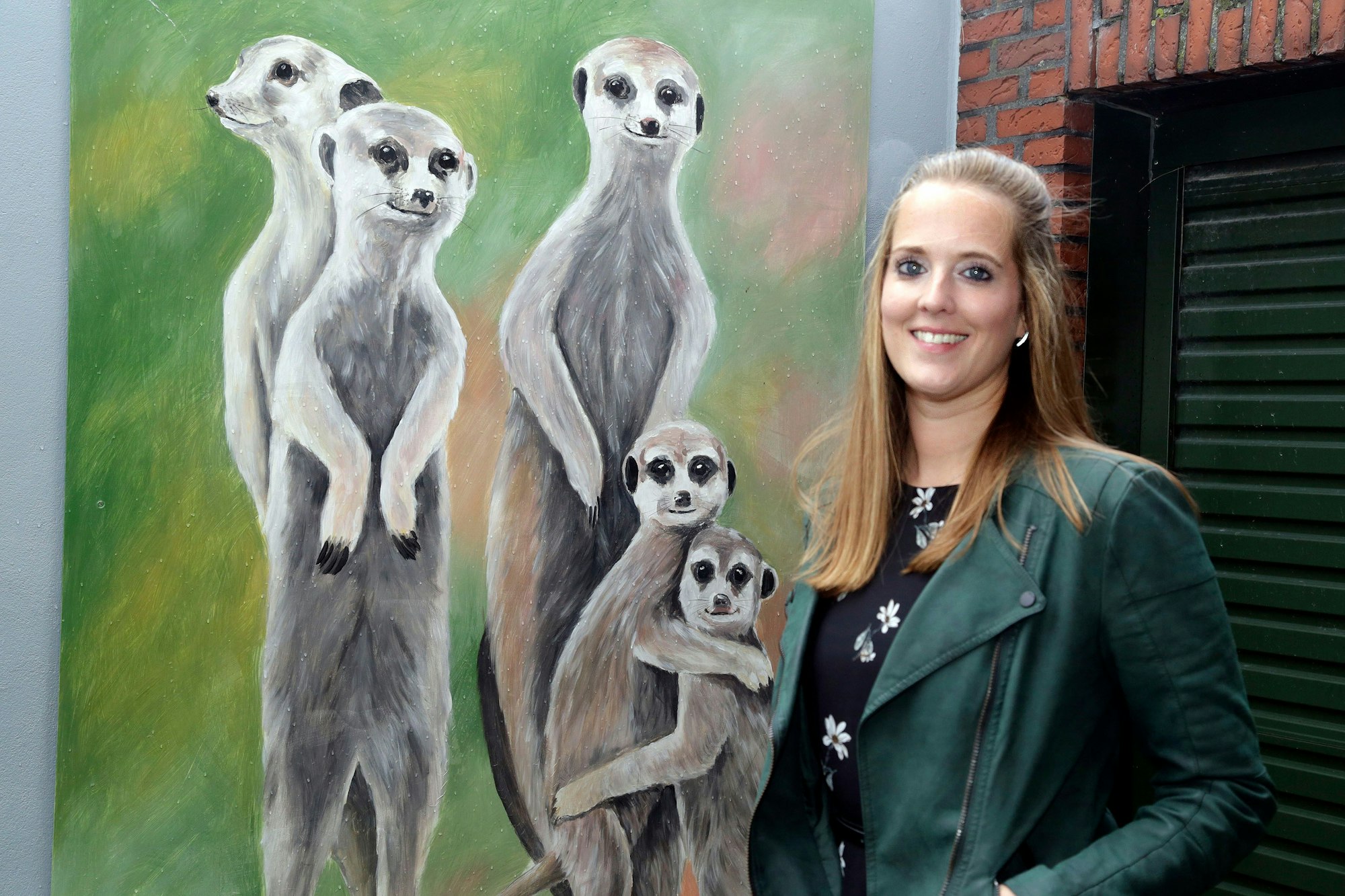 Sandra Salzig vor Erdmännchen-Kunstwerk an die Garagenwand.