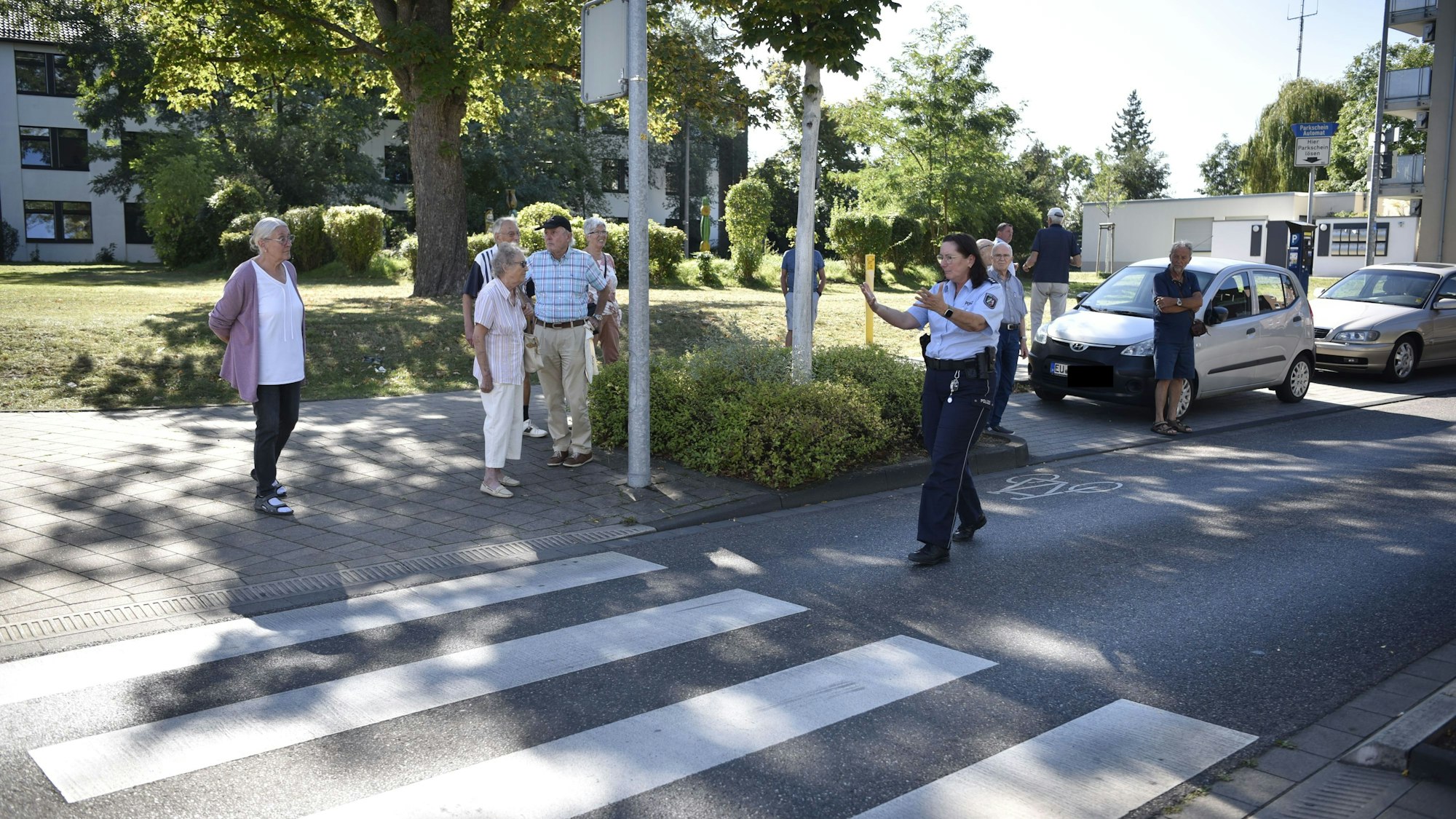 Die Polizistin Lydia Hüpgen gibt den Senioren an einem Zebrastreifen Tipps für das richtige Verhalten im Straßenverkehr.