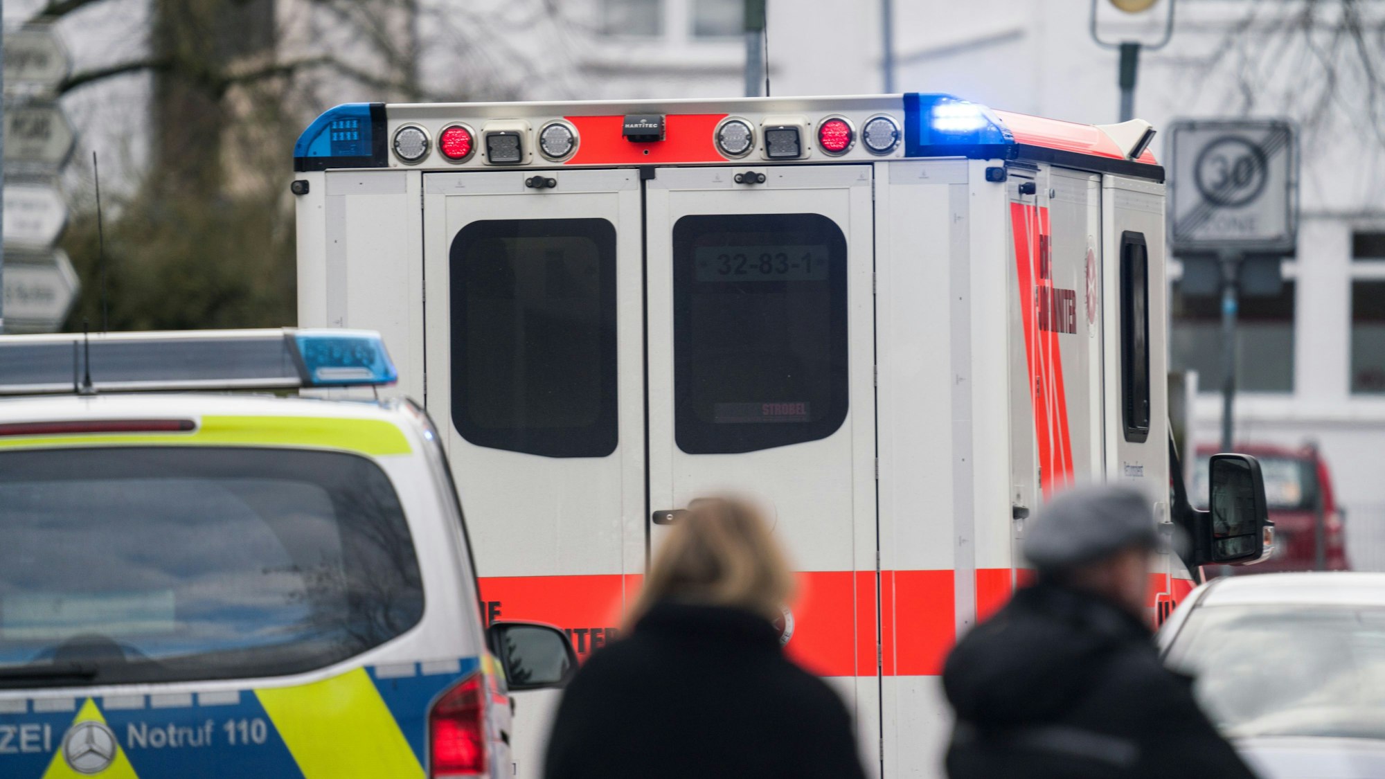 Ein Rettungswagen und ein Polizeiwagen stehen nach einem Einsatz in einer Straße.