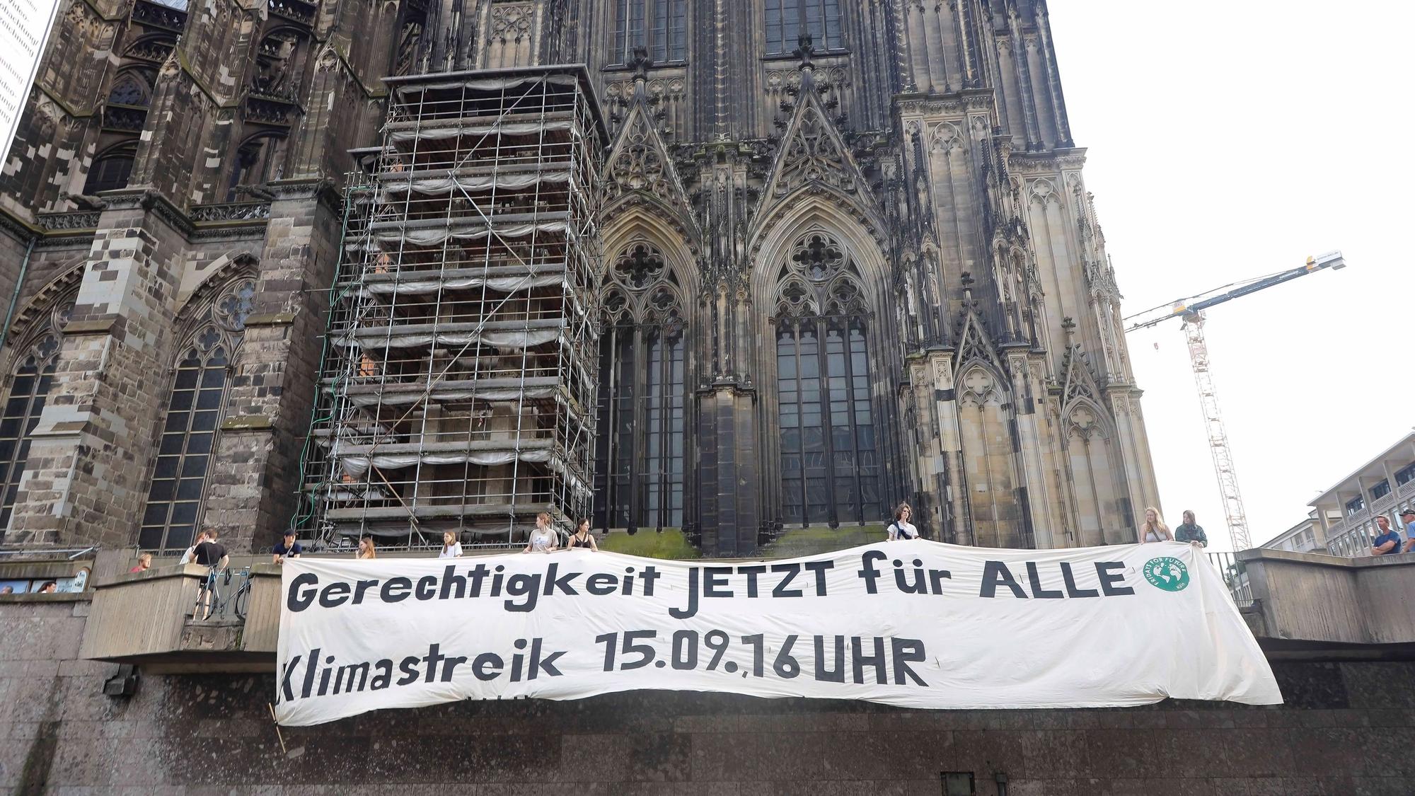Die Klimaschutzorganisation Fridays For Future hangen vor dem Dom ein Banner mit dem Schriftzug „Gerechtigkeit jetzt für alle - Klimastreik 15.9, 16 Uhr“ auf.