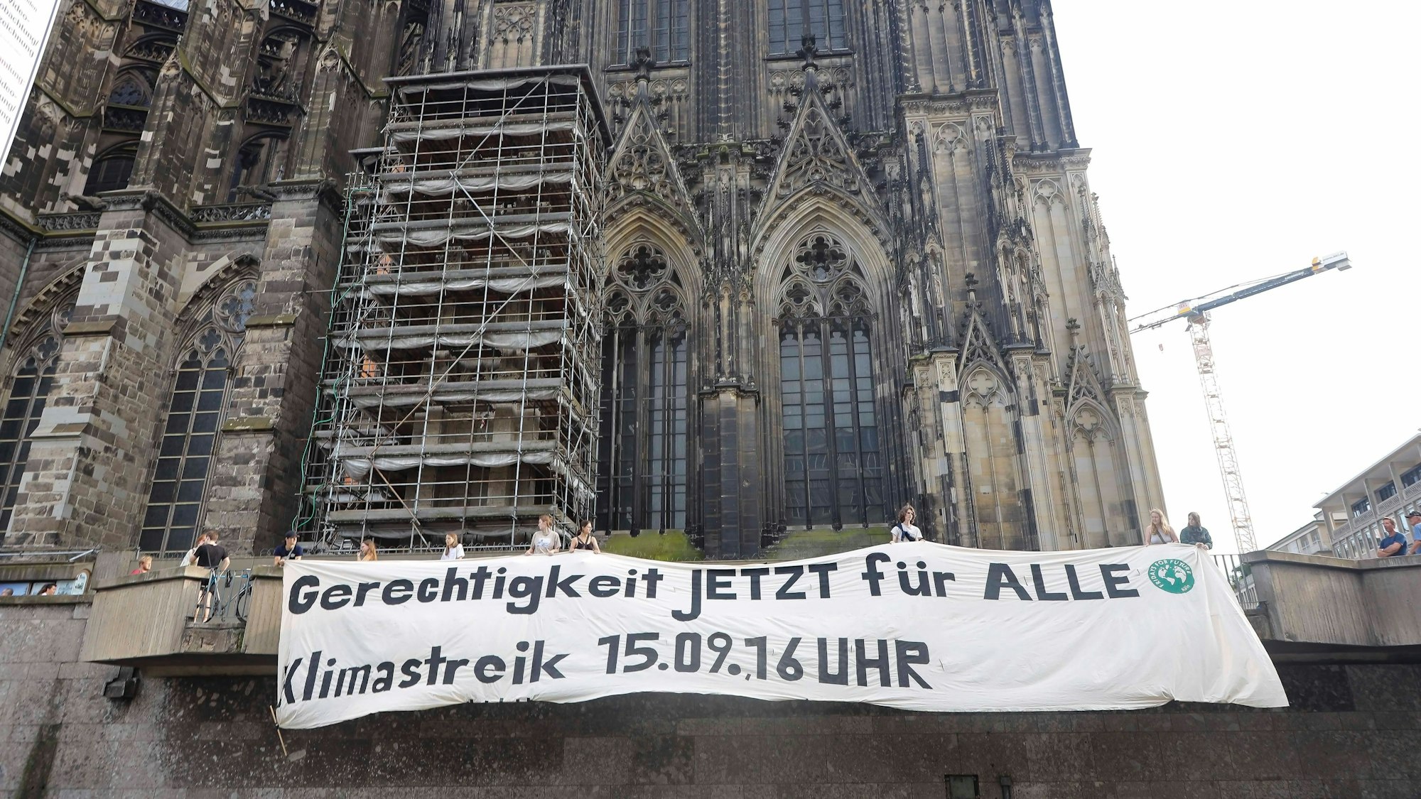 Die Klimaschutzorganisation Fridays For Future hangen vor dem Dom ein Banner mit dem Schriftzug „Gerechtigkeit jetzt für alle - Klimastreik 15.9, 16 Uhr“ auf.