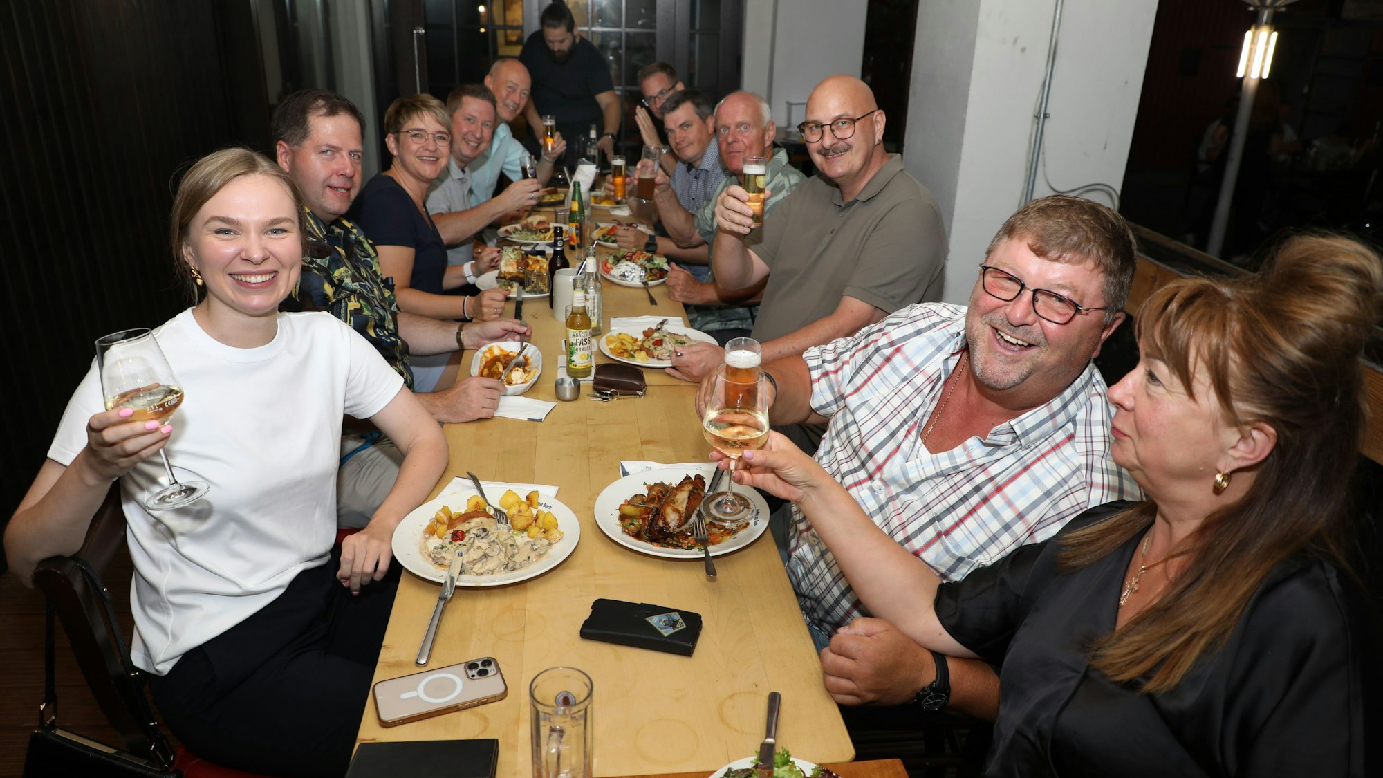 Menschen sitzen mit Getränken an einem Tisch im Wirtshaus Am Bock
