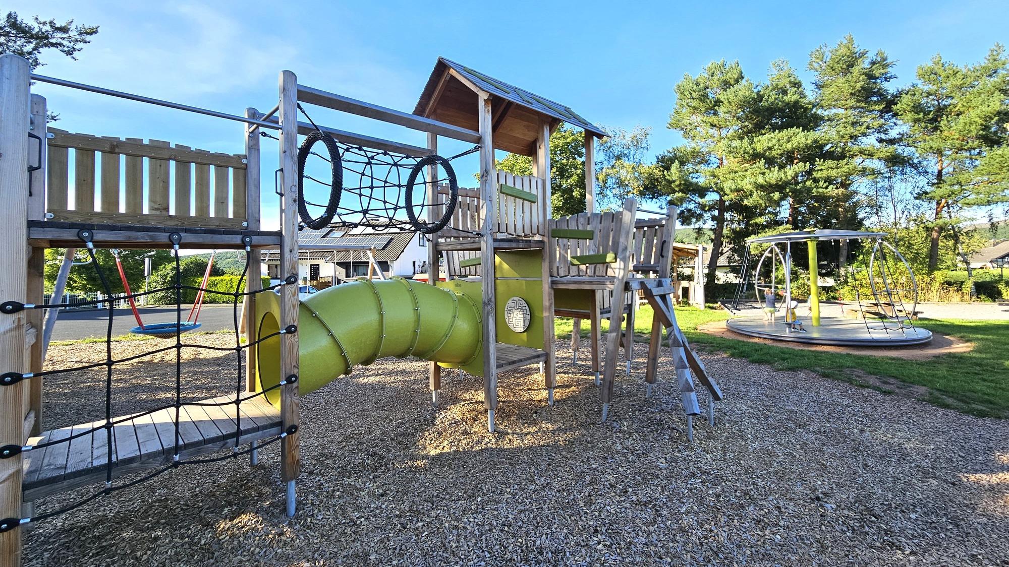 Das Bild zeigt einen modernen Spielplatz mit verschiedenen Kletter- und Spielmöglichkeiten.