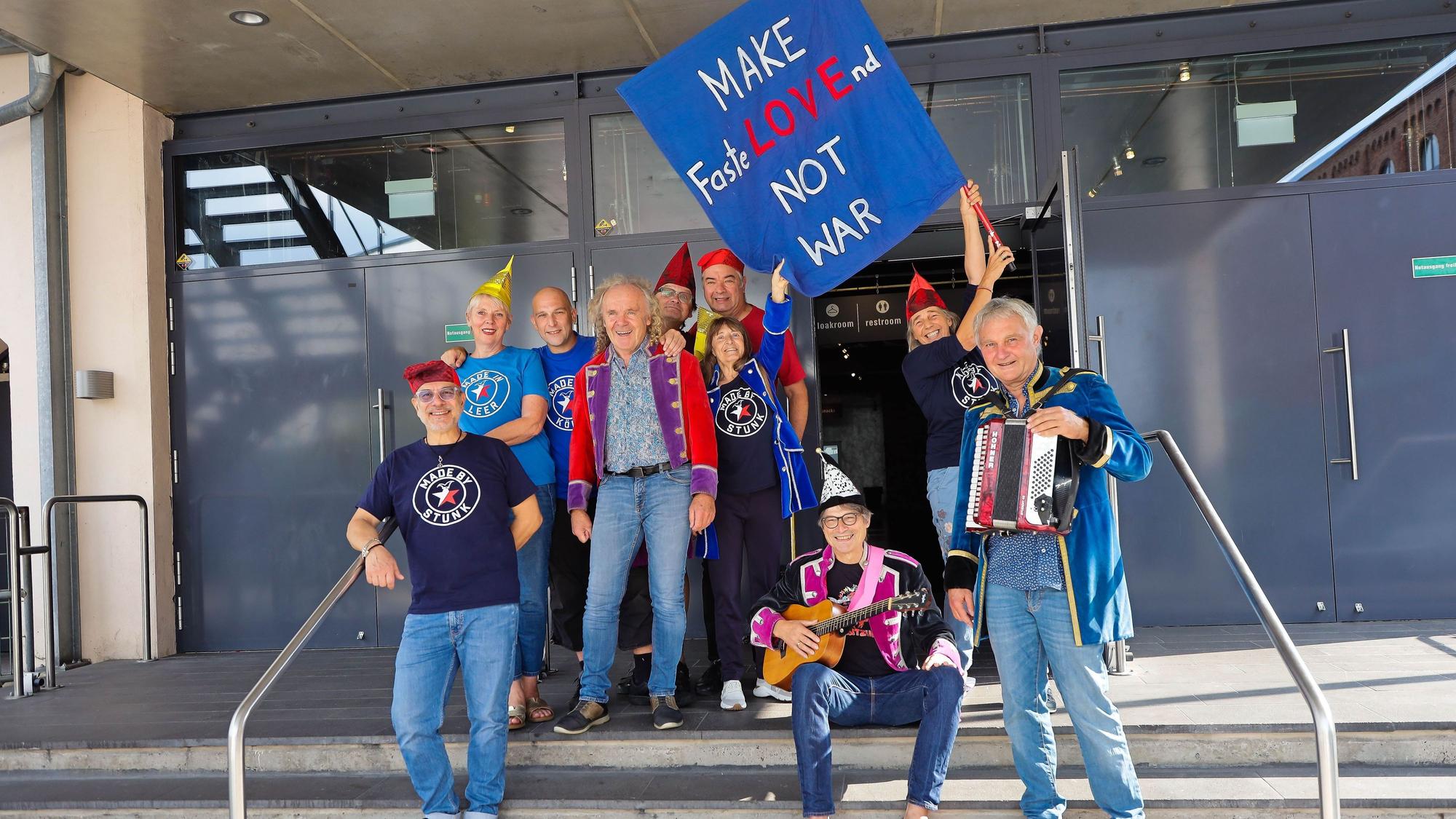 Eine Gruppe Stunker auf den Treppen vor dem E-Werk, sie halten eine Fahne mit der Aufschrift: Make Fastlovend, not war.
