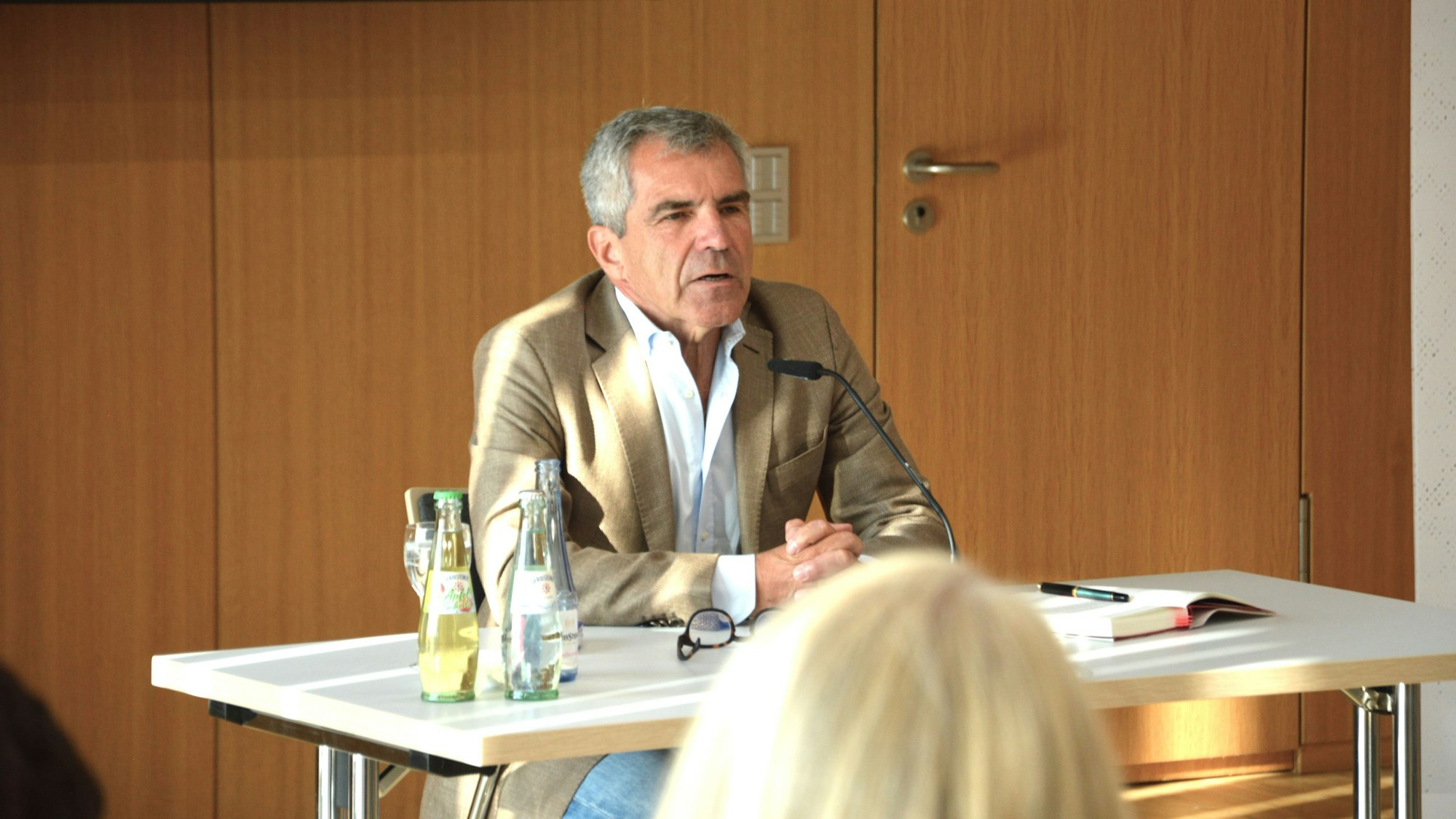 Der Journalist Hans Demmel sitzt an einem Tisch.